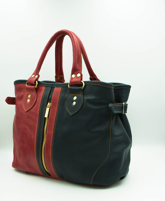 Two-tone leather handbag in red and navy, gold accents, dual handles, central zipper, and side straps for a stylish, functional design.